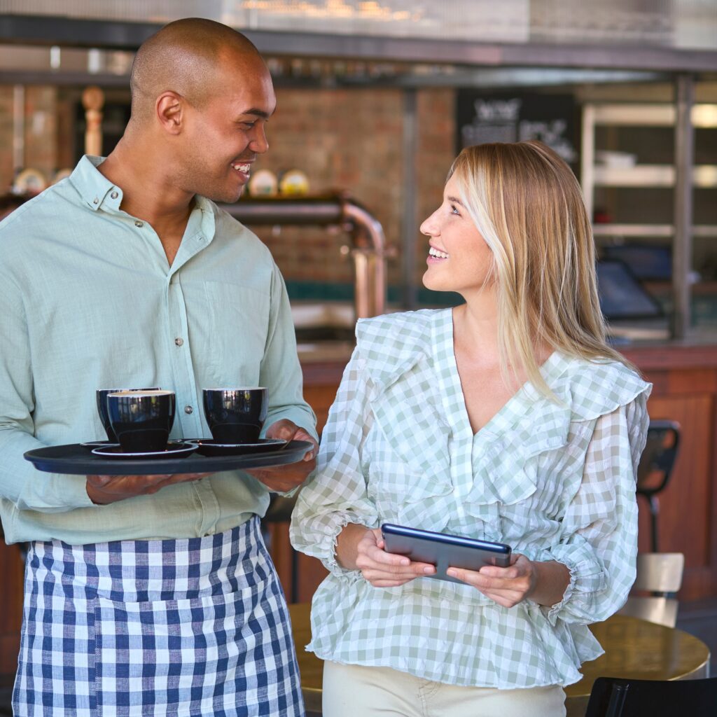 Female Manager Holding Digital Tablet Working With Staff In Restaurant Or Coffee Shop