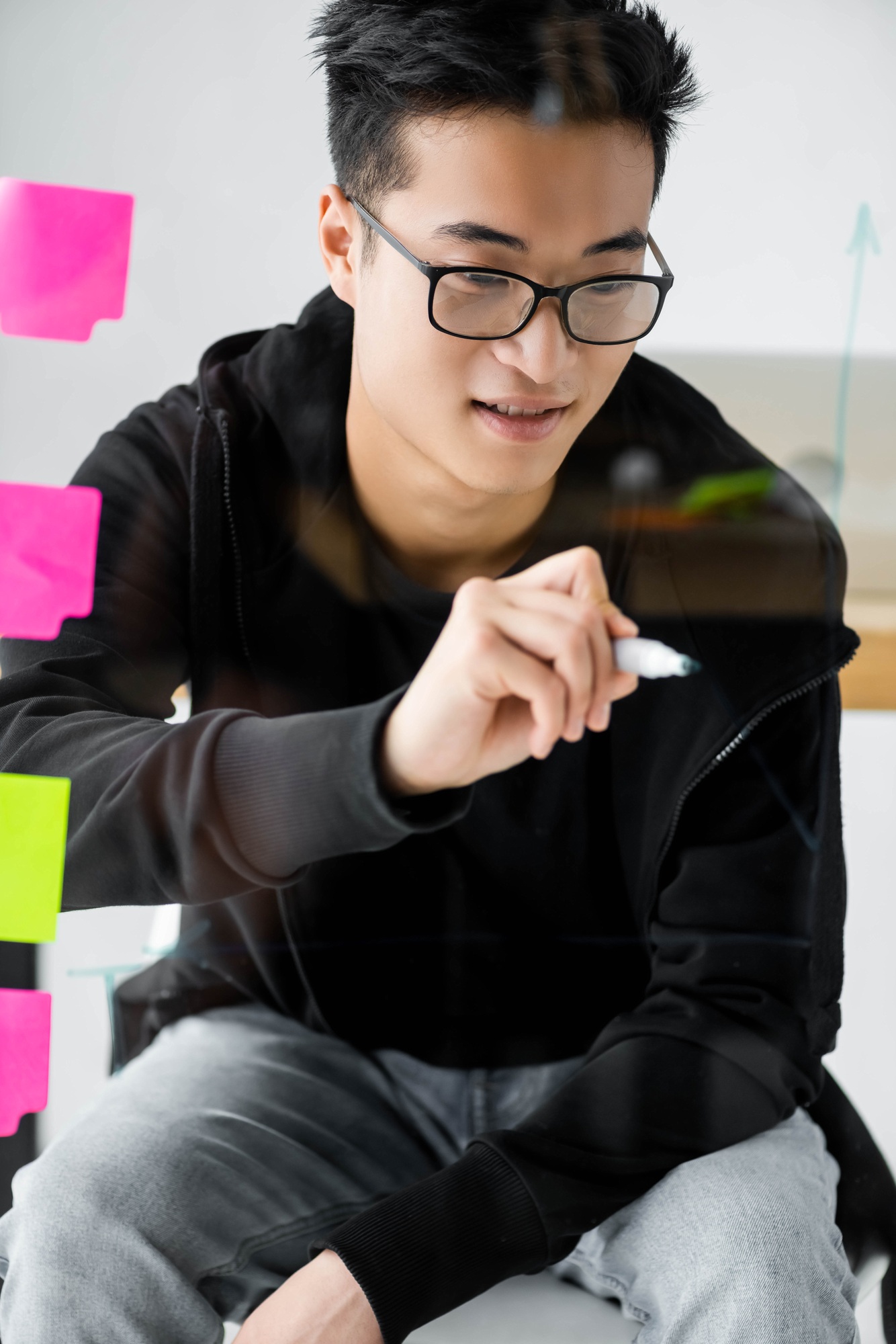 smiling asian seo manager in glasses painting arrow on glass