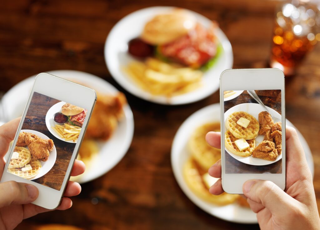 two friends taking photo of their food with smartphones
